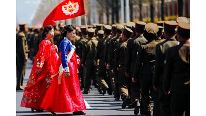 Mujeres con ropa tradicional caminan junto a soldados norcoreanos después de la ceremonia de apertura para un complejo residencial en la calle Ryomyong en Pyongyang