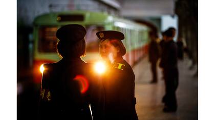 Trabajadores del ferrocarril charlan mientras el tren llega a una estación de metro visitada por periodistas extranjeros en el centro de Pyongyang