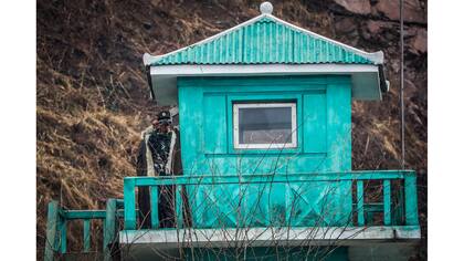 Un soldado norcoreano mira a través de binoculares desde una torre de vigilancia en Sinuiju, Corea del Norte, hacia la provincia china de Liaoning