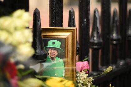 Una fotografía enmarcada de la reina Isabel II de Gran Bretaña se ve en las rejas del Palacio de Buckingham en el centro de Londres el 8 de septiembre de 2023
