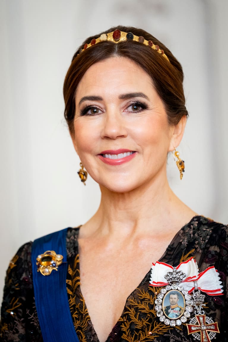 El broche Pearl Poiré de perla y diamantes que la reina Mary llevó sobre un traje azul. En la otra imagen, con la diadema de oro y camafeos que estuvo en las sombras por más de 140 años