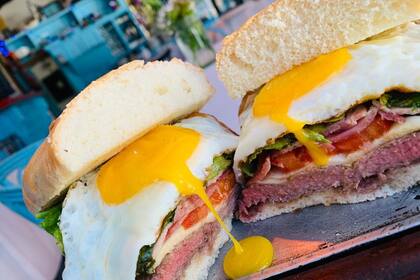 Queso, panceta ahumada, tomates confitados, rúcula orgánica y un huevo de campo frito con la yema bien cremosa forman parte del sándwich de chivito de Bar de Carnes.