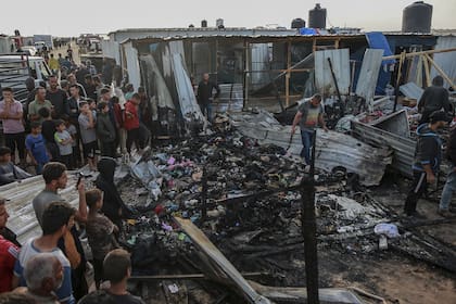 Palestinos observan la destrucción tras un ataque israelí donde se alojaban personas desplazadas en Rafah, Franja de Gaza, lunes 27 de mayo de 2024. 