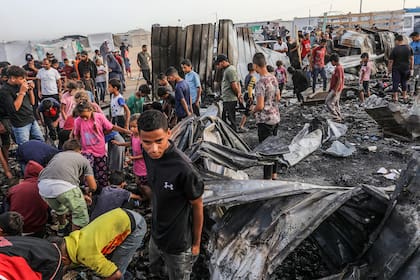  Palestinos inspeccionan sus tiendas destruidas tras un ataque aéreo israelí, que causó numerosos muertos y heridos, en la zona de Al-Mawasi, bombardeada con varios misiles sobre las tiendas de los desplazados al oeste de la ciudad de Rafah, en el sur de la Franja de Gaza.