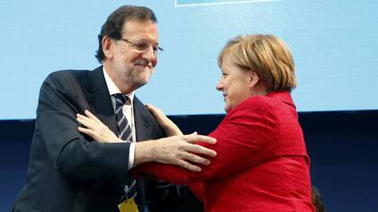 Rajoy y Merkel se saludan en un acto en Madrid esta mañana