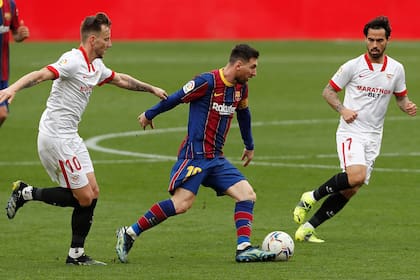 Rakitic de Sevilla y Suso y Messi de Barcelona pelean por el balón durante un partido de fútbol de la Liga española entre Sevilla y Barcelona en febrero de 2021