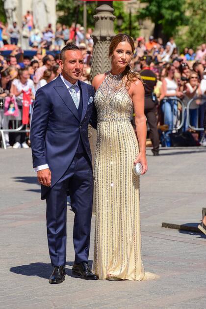 Santi Cazorla, compañero de la Selección Española del novio, con su mujer, Úrsula Santirso, con un vestido amarillo claro de escote «halter», cuajado de pedrería y abalorios en plata.
