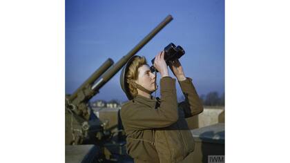 Un miembro del Servicio Territorial Auxiliar (ATS) mira por binoculares junto a un can antiareo de 3,7 pulgadas, Diciembre 1942.