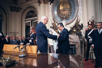 Raúl Alfonsín recibe la banda presidencial en 1983, de la mano de Reynaldo Bignone