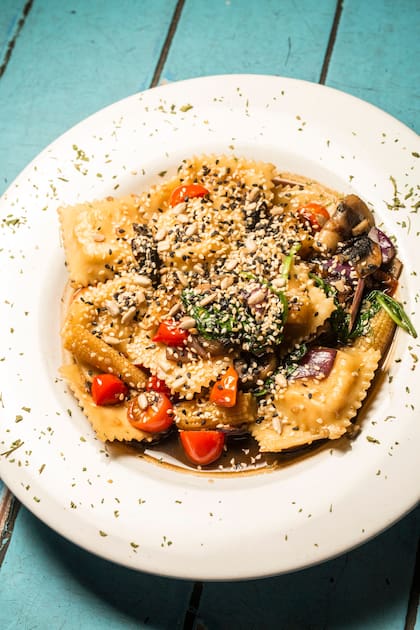 Ravioles de salmón rosado salteados con salsa de ostras, tomates cherry, choclitos, pak-choy y hongos.