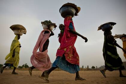 Refugiadas sudanesas cargan sus pertenencias en un campo de refugiados de Chad