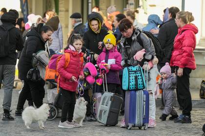 Refugiados con niños esperan a recibir un transporte tras huir de la guerra en la vecina Ucrania en la estación de tren de Przemysl, Polonia, el jueves 24 de marzo de 2022. 