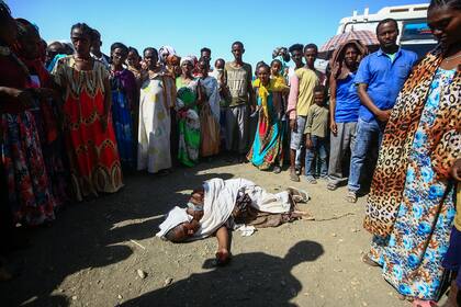 Refugiados etíopes que huyeron de los combates en la región de Tigray rodean a una mujer que colapsó en el centro de recepción fronterizo Village 8 en el estado de Gedaref, en el este de Sudán, el 20 de noviembre de 2020