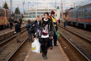 Refugiados que huyen de la guerra de la vecina Ucrania caminan en un andén tras bajar de un tren el miércoles 2 de marzo de 2022, en Zahony, Hungría. (AP Foto/Balazs Kaufmann)