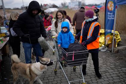 Refugiados son asistidos por un voluntario después de cruzar desde Ucrania en Medyka, Polonia