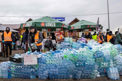Un voluntario reparte agua para los refugiados
