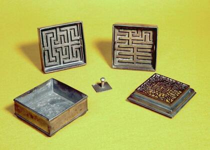 Reloj de incienso desarmado: de izquierda a derecha: base, dos plantillas y tapa. En el centro, regulador