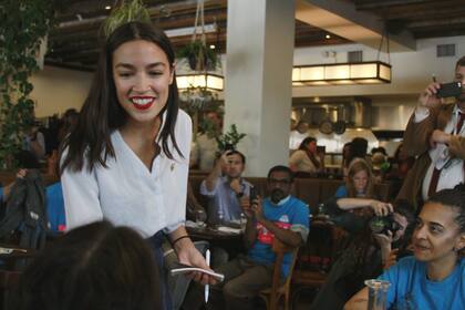 Rep. Alexandria Ocasio-Cortez, D-N.Y., waits on tables at restaurant in the Queens borough of New York, Friday, May 31, 2019. Leveraging her background as a waitress and bartender, Ocasio-Cortez took orders and mixed mixed margaritas for about half an hour as part of a publicity event for her push t
