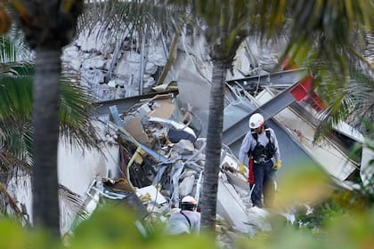 Rescatistas caminan entre los escombros de parte de un edificio de 12 plantas que se vino abajo, el 24 de junio de 2021, en Surfside, Florida. (AP Foto/Marta Lavandier)