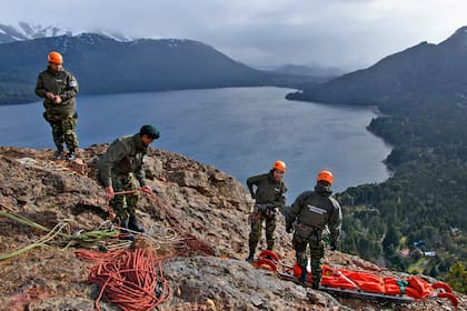 Cuatro gendarmes preparan las cuerdas y la camilla especial con la que descenderán, en forma vertical, por una pared de piedra.