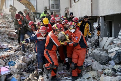 Rescatistas sacan a un migrante sirio de entre los escombros de un edificio destruido en Antioquía, en el sur de Turquía