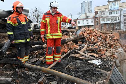 Rescatistas ucranianos acceden a los escombros para despejar en un edificio residencial, parcialmente destruido tras un ataque con misiles en Kharkiv 