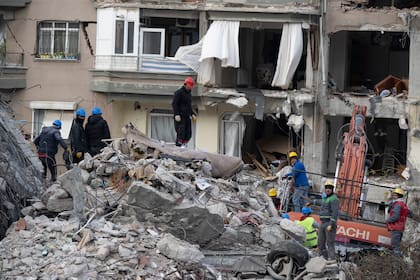 Rescatistas y bomberos buscan sobreviventes entre los escombros de un edificio en Antakya, Turquía