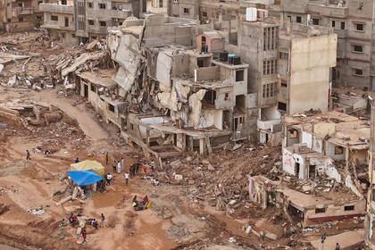 Rescatistas y parientes de víctimas colocan carpas ante edificios derruidos en Derna, Libia, tras graves inundaciones que dejaron destrucción total en varias ciudades el lunes 18 de septiembre de 2023.