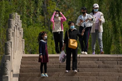 Residentes con mascarillas recorren el parque Longtan de Pekín, el domingo 16 de abril de 2023. 