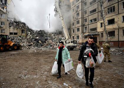 Residentes llevan sus pertenencias de un edificio residencial destruido tras un ataque con misiles, en Dnipro el 15 de enero de 2023, en medio de la invasión rusa de Ucrania.