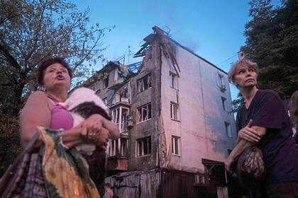 Residentes locales se encuentran frente a su casa, gravemente dañada por un ataque ruso en Kiev, Ucrania, el jueves 10 de julio de 2025.
