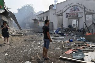Residentes observan negocios destruídos luego de un ataque con cohetes en Sloviansk, 3 de julio de 2022. 
