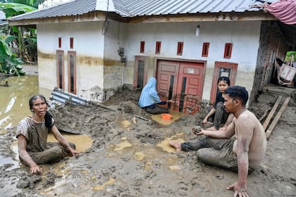 Residentes retiran barro profundo de la entrada de una vivienda inundada en Meureudu, en el distrito de Pidie Jaya, en la provincia de Aceh, Indonesia, el 28 de noviembre de 2025