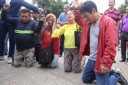 Residentes rezan mientras agentes de policía acuden en ayuda de un guardia de seguridad que tenía una especie de chaleco con explosivos pegado al torso, en Guayaquil, Ecuador, el jueves 30 de marzo de 2023.