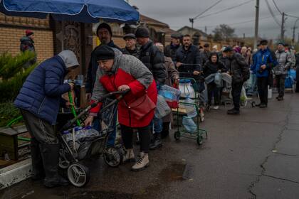 Residents queue to fill containers with drinking water in Kherson, southern Ukraine, Sunday, Nov. 20, 2022. Russian forces fired tank shells, rockets and other artillery on the city of Kherson, which was recently liberated from Ukrainian forces. (AP Photo/Bernat Armangue)