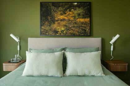 Respaldar de tusor suspendido y mesas de luz flotantes a medida enchapadas en petiribí y (Cas a Cas) con apliques amurados (Paraná 201). Pared en ‘Verde Plantación’ (Alba). Enmarcada, foto de Maia Croizet.