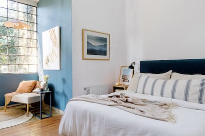 Respaldo de cama (Casa Perri). Cubreedredón (Aruna). Almohadones (Ripio). Cortinas enrollables (Puerto de Frutos). Lámpara colgante y banqueta (Malacara Taller). En la pared, ‘Gris Nórdico’ (Alba).