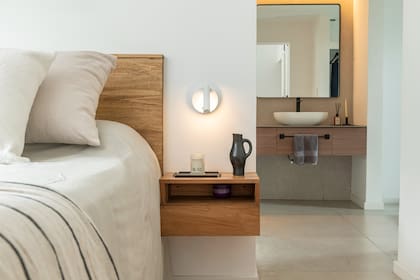 Respaldo y mesa de luz realizados a medida por el estudio, en madera Petiribi. Aplique de pared Lit (Lumishop), sobre mesa de luz, bandeja de chata (Estudio Te) y vela (Alto rancho).