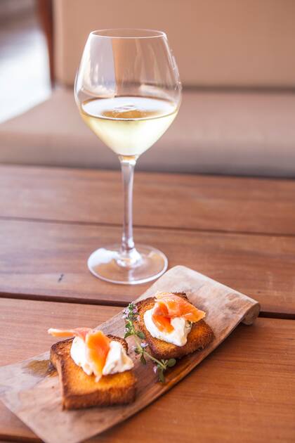 Huevo poché y salmón sobre tostada y copa de Sauvignon Blanc en la mesa de Piedra Infinita.