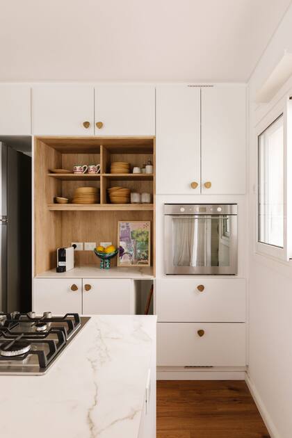 Revestido de melamina símil madera y sin puertas, el nicho resalta entre los frentes blancos.