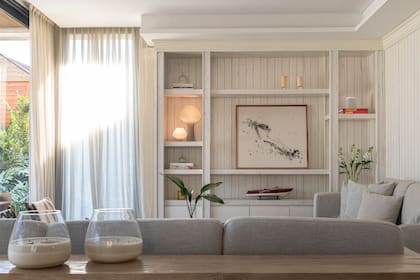 Revestimiento de pared de madera enchapada y laqueada, biblioteca y cortinas de gasa off white (todo de Métier Studio).