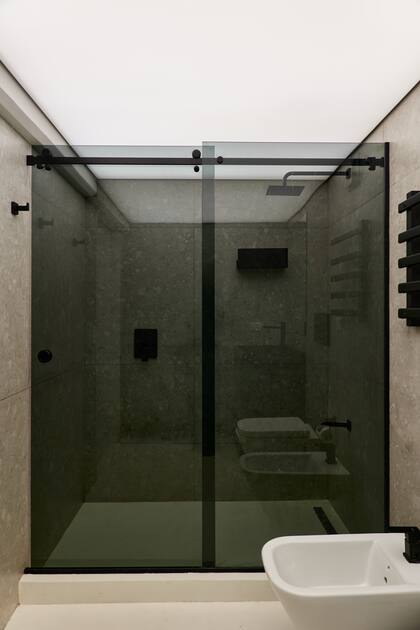 Revestimiento de porcelanato 'Pietra Lombarda' (SBG), grifería accesorios negros (Peirano) y mampara es de vidrio negro. Techo de tela de PVC tensada (Tela Wagg)