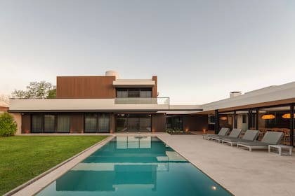 Revestimiento de WPC símil madera en dos colores: el más claro para alivianar la planta alta y el más oscuro para acentuar la sombra de la planta baja. Reposeras (Mike Outdoor).