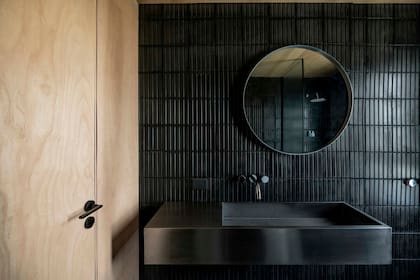 Revestimiento y piso de calcáreos negros tipo vainilla confeccionados por un artesano de Luján. Lavatorio de acero inoxidable diseñado por el Estudio Plöck, a cargo de toda la obra. Grifería ‘Fabric’ (Peirano).