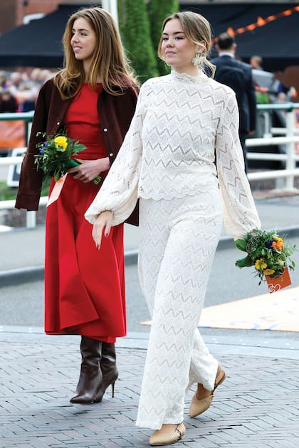 Alexia, con un vestido rojo de la casa española Helsa, botas de caña alta Gianvito Rossi y clutch de Sarah’s Bag, recorre las calles de la ciudad junto a su hermana menor, Ariane, que vistió un conjunto de blusa y palazzo de macramé blanco de Twinset y bag de rafia de Marina Raphael