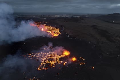  Así se ve el flujo brillante de magma y la humareda del volcán