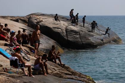 Un hombre salta de la piedra de Arpoador en medio de una ola de calor récord en la playa de Ipanema el 15 de noviembre de 2023 en Río de Janeiro, Brasil