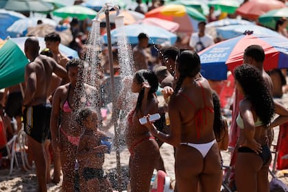 Las personas se duchan en medio de una ola de calor récord en la playa de Ipanema el 15 de noviembre de 2023 en Río de Janeiro