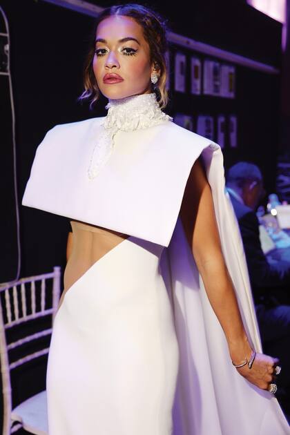 Rita Ora, que fue la encargada del show, eligió para el escenario un vestido blanco con estructura geométrica de cuello alto que remataba en una capa.