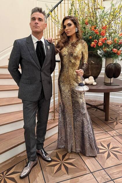Robbie Williams y su mujer, Ayda Field, combinaron sus looks con un toque plateado: los zapatos del cantante y la falda del vestido de la actriz diseñado por Reem Acra, más un clutch modelo UFO Orbiter de Judith Leiber.